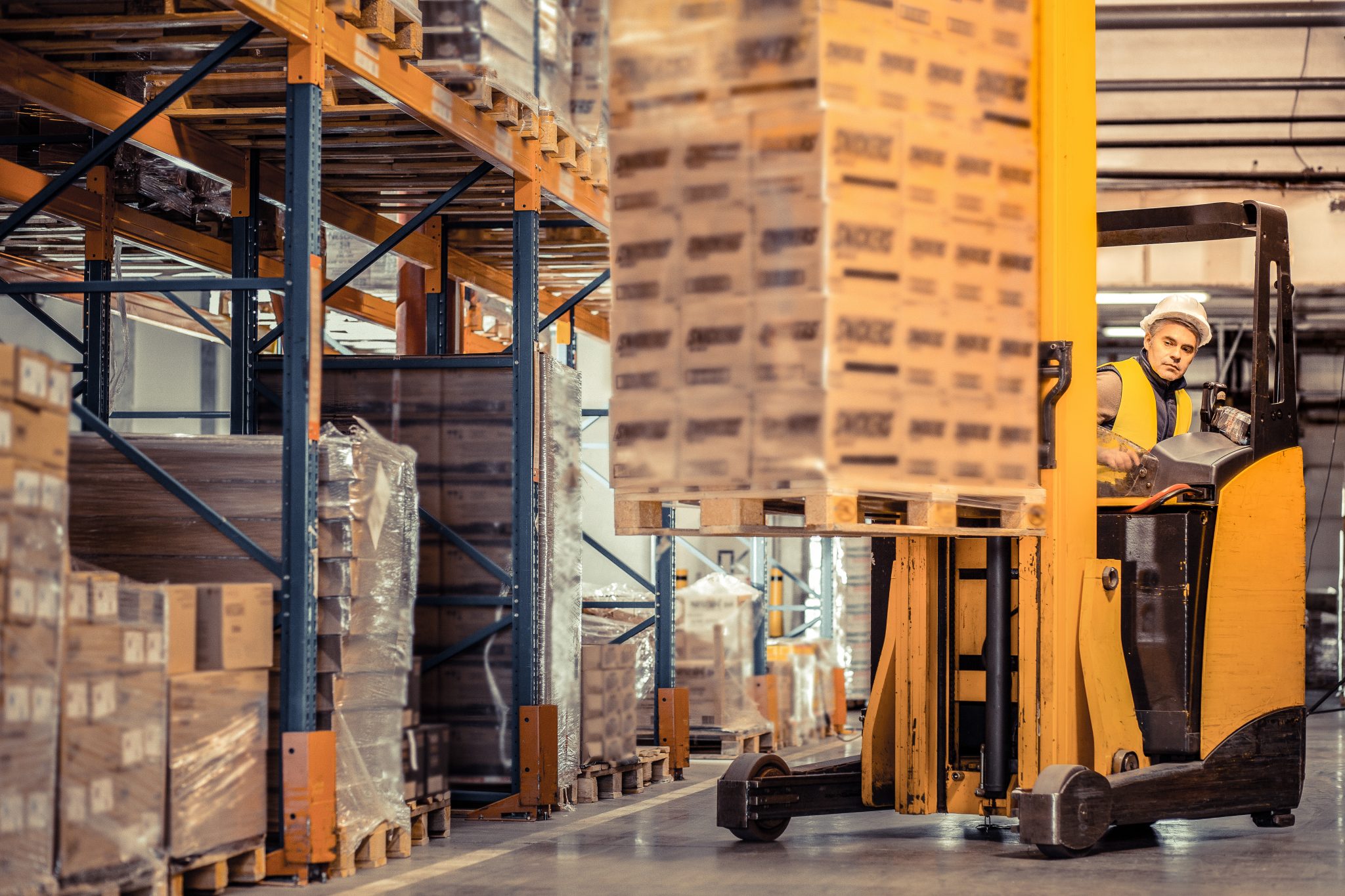 Forklift operator moving pallets in a warehouse